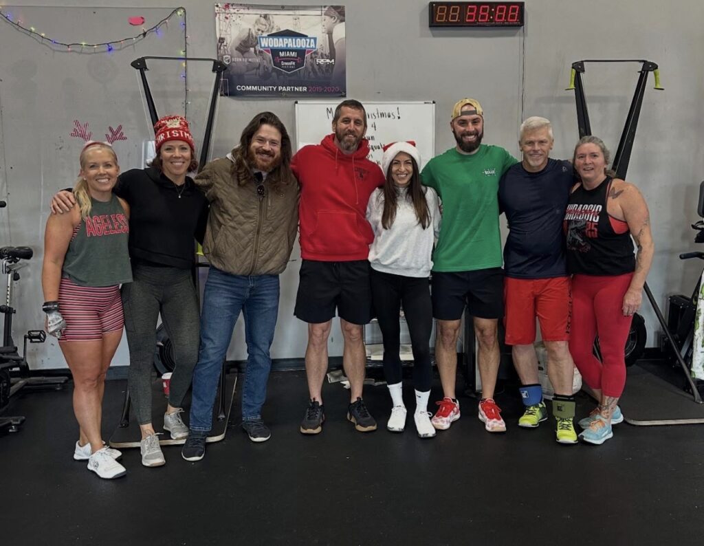 A group of eight fitness enthusiasts poses together in a gym setting